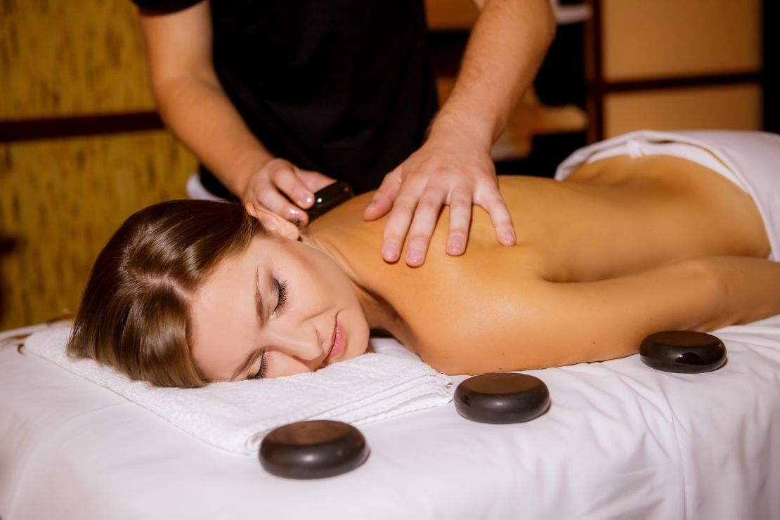 massage therapist performing hot stone massage